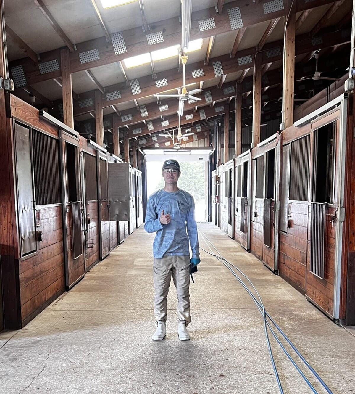 Daniel in the clean horse barn aisle at Pine Hill Farm