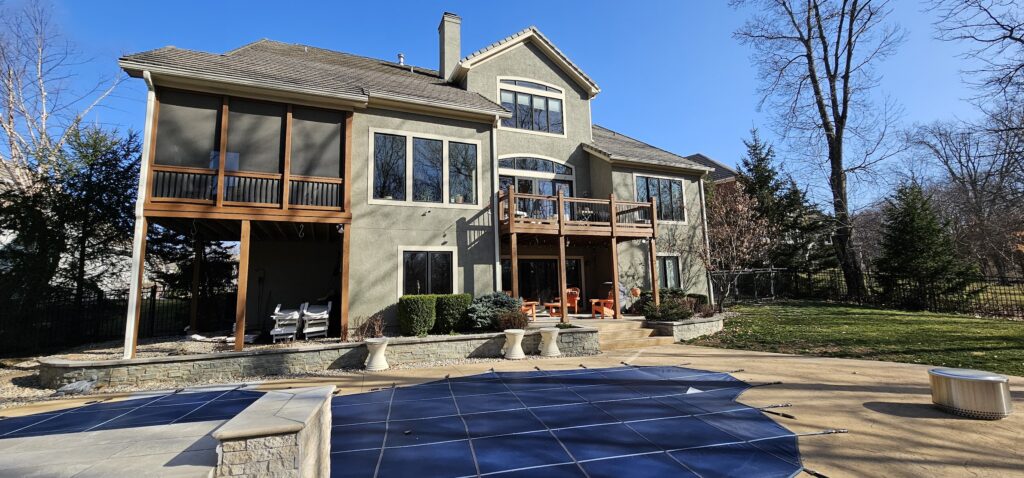 Rear elevation of a luxury stucco home with pool deck screened porch and deck in Riss Lake Parkville MO