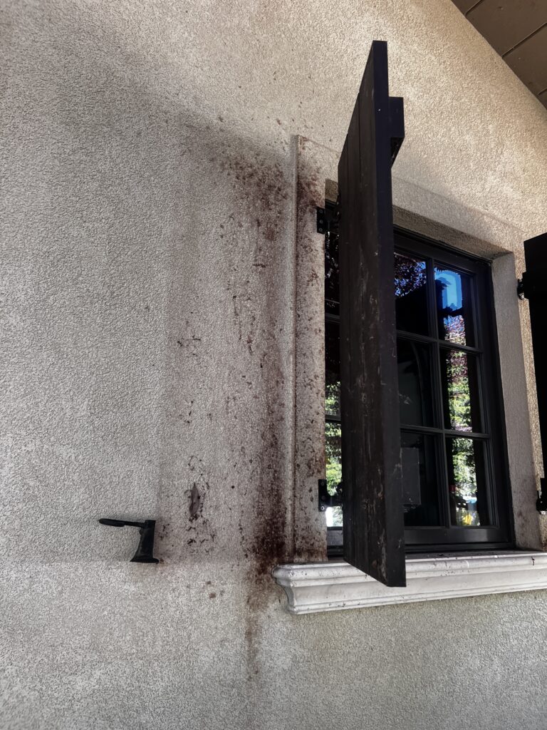 Heavy organic staining around window frame on stucco exterior before KC Splash soft washing in Mission Hills KS
