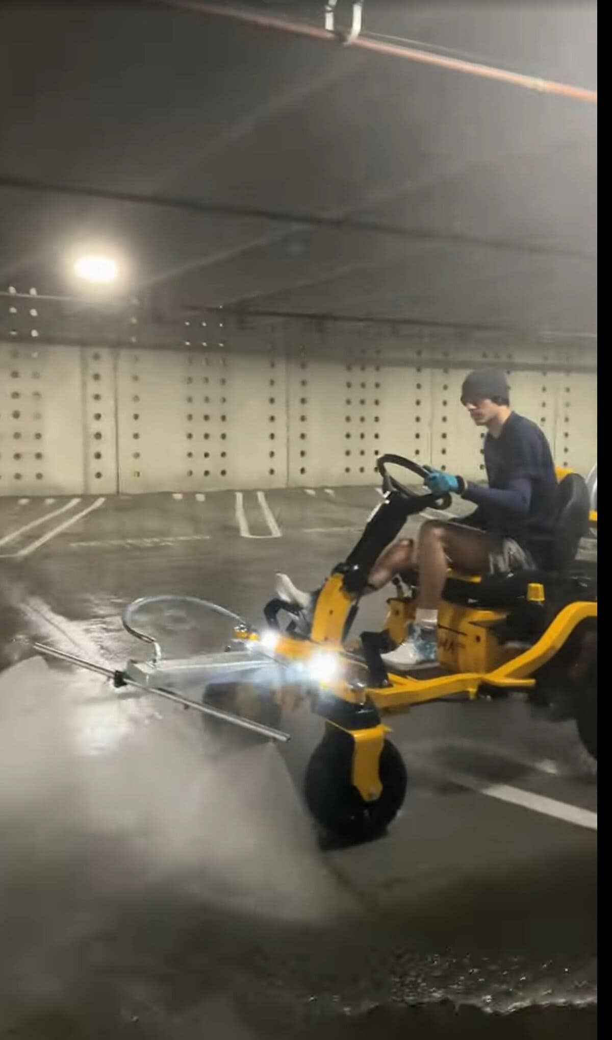 Side profile of The Beast ride-on surface cleaner delivering hot water pressure to garage floor