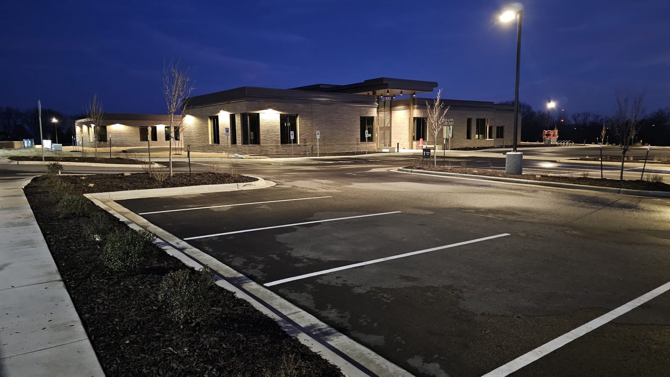 KC Splash Beast ride-on surface cleaner in front of Rolling Hills Library sign in St. Joseph Missouri — post-construction parking lot cleaned to grand opening standard