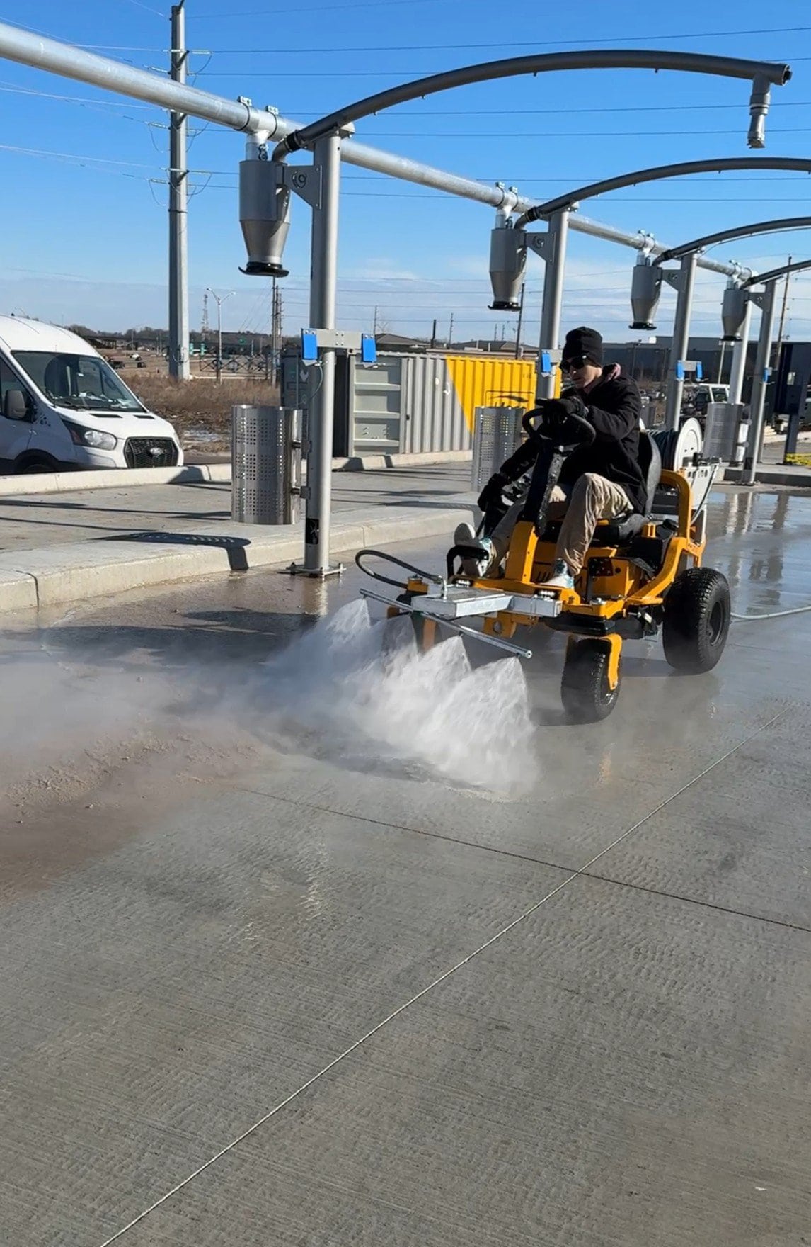 KC Splash crew member operating The Beast surface cleaner inside Tidal Wave Auto Spa car wash facility
