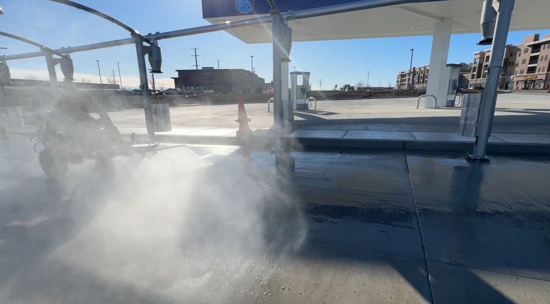 Large hot water steam cloud rising during post-construction cleaning at Tidal Wave Auto Spa