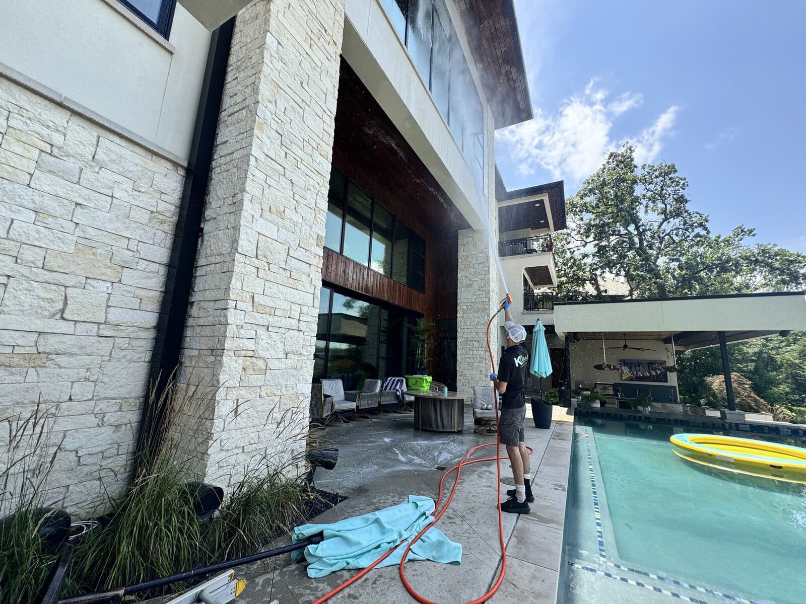 Rear elevation of a modern glass-and-stone lakefront estate on Weatherby Lake before KC Splash soft wash