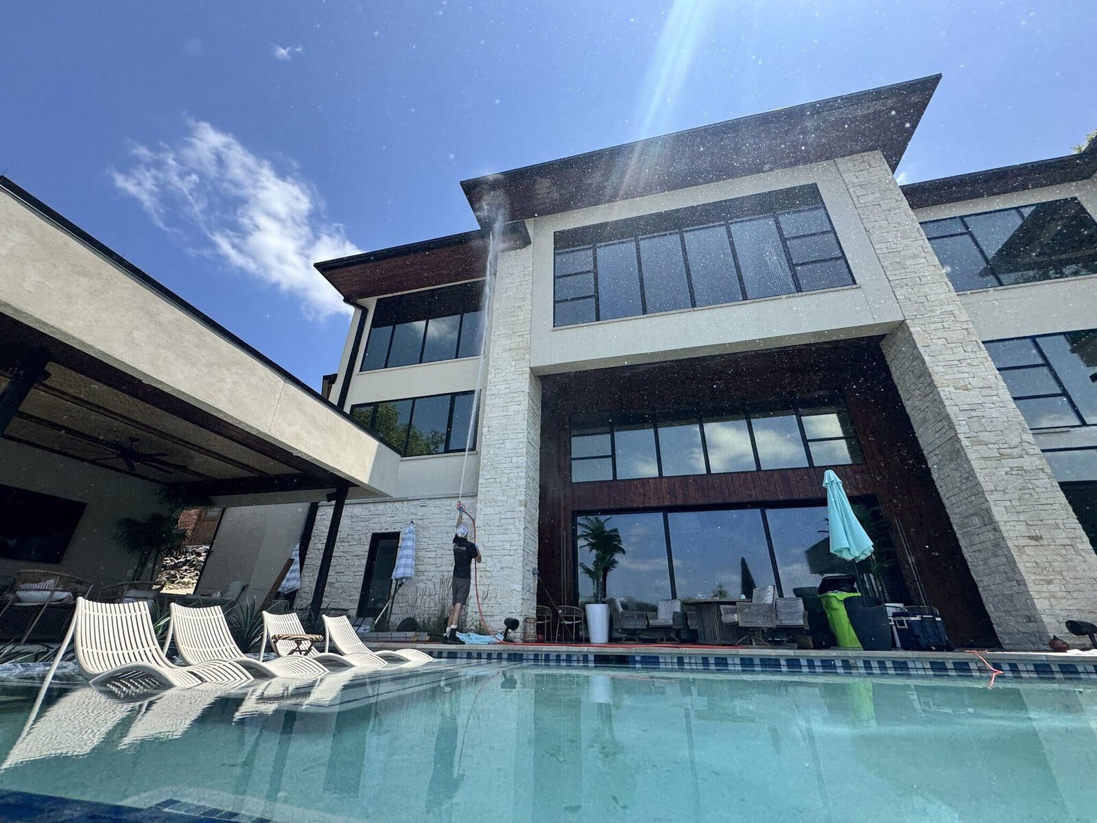 KC Splash technician soft washing and window cleaning the lakeside face of a modern estate on Weatherby Lake, Kansas City