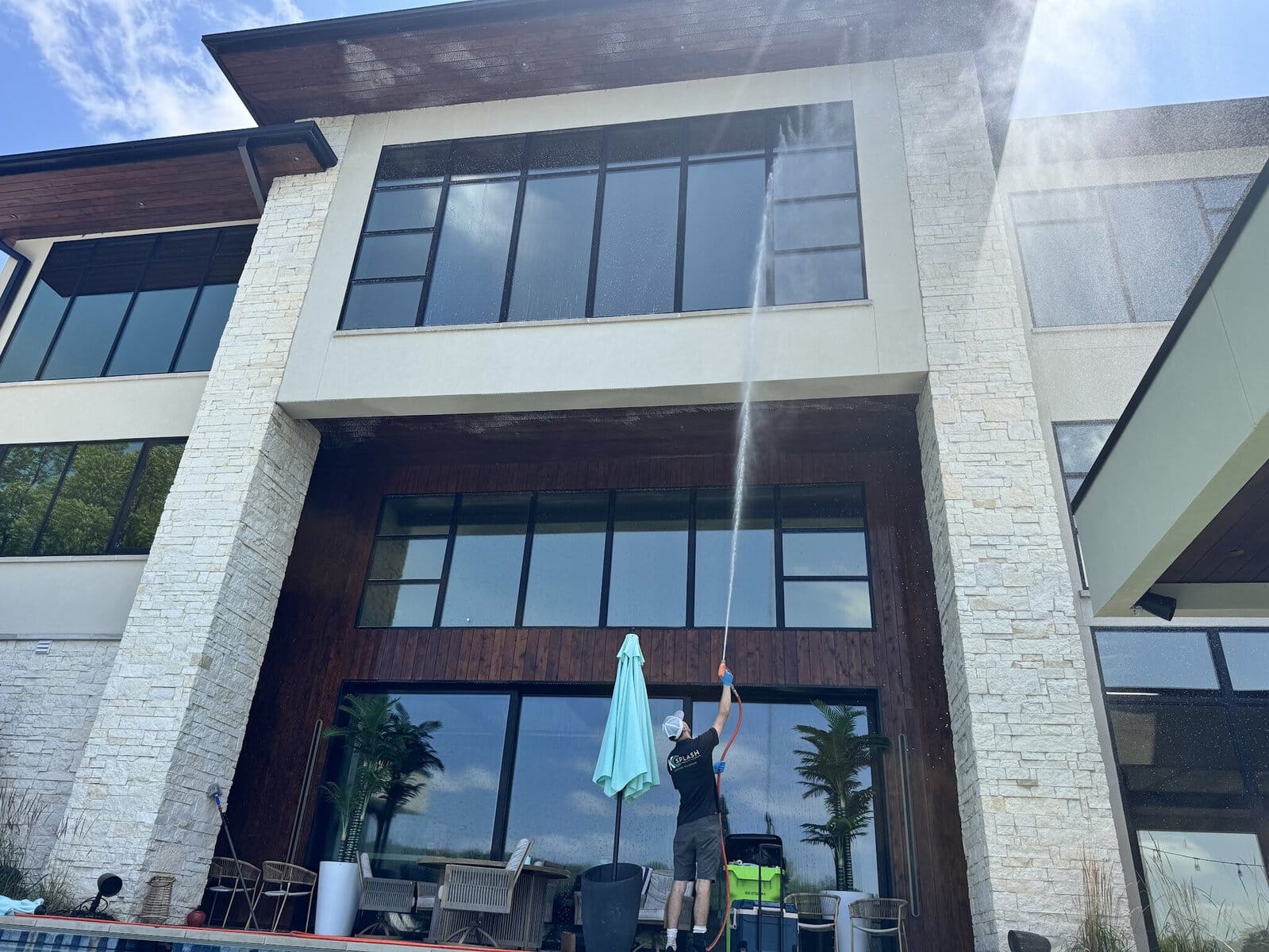 KC Splash technician exterior window cleaning tall glass walls on a modern Weatherby Lake estate