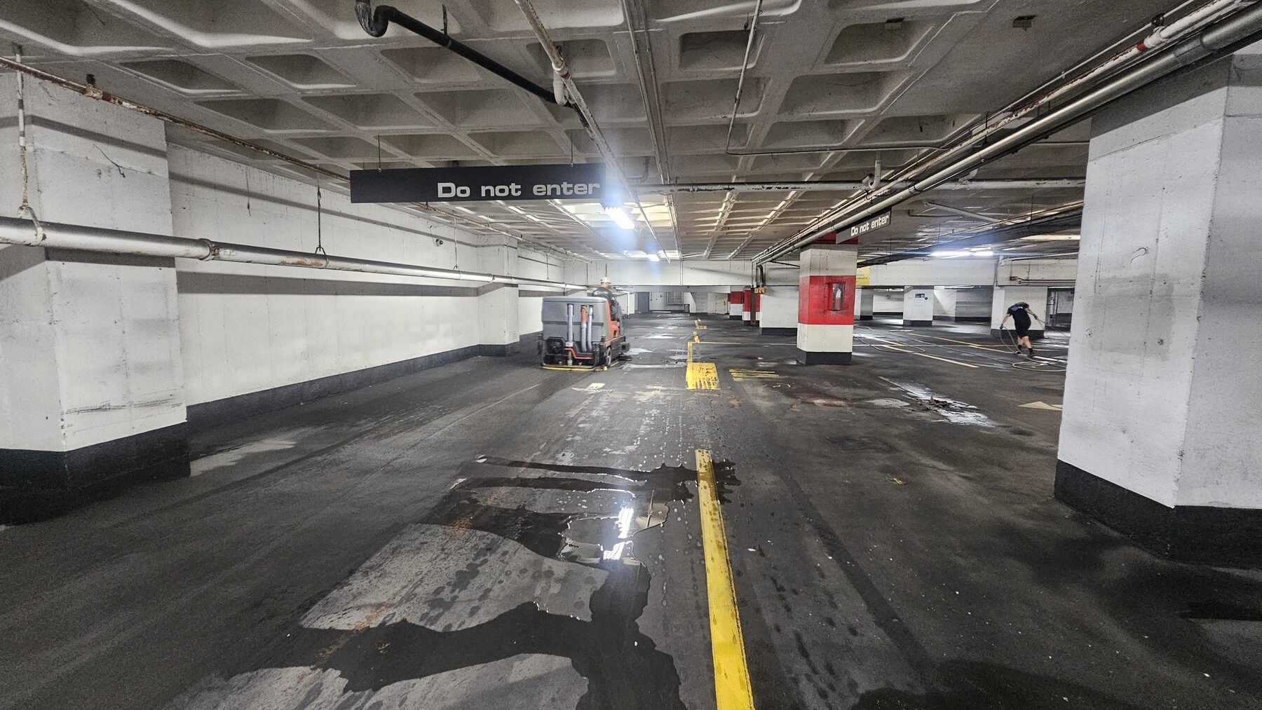 Lower level of the Lightwell parking garage during cleaning, ride-on floor scrubber and crew member working